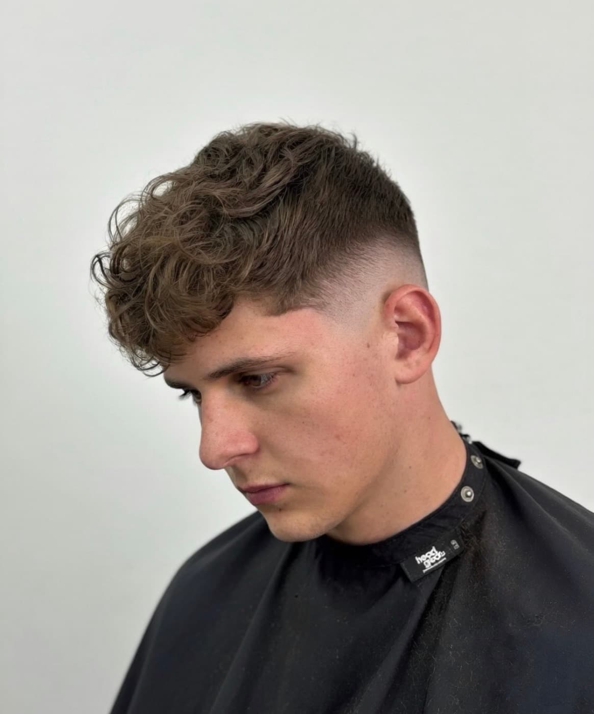 Loose curls left long on top over a clean mid fade